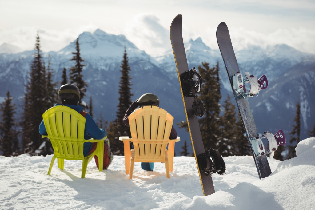 couple-sitting-chair-by-snowboards-snow-covered-mountain.jpg