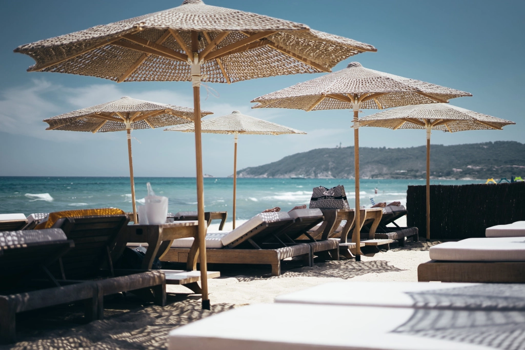 selective-wide-shot-of-brown-wooden-loungers-under-parasols-by-the-beach.jpg